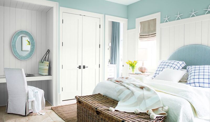 A light-blue painted bedroom with white trim and built-in vanity area.