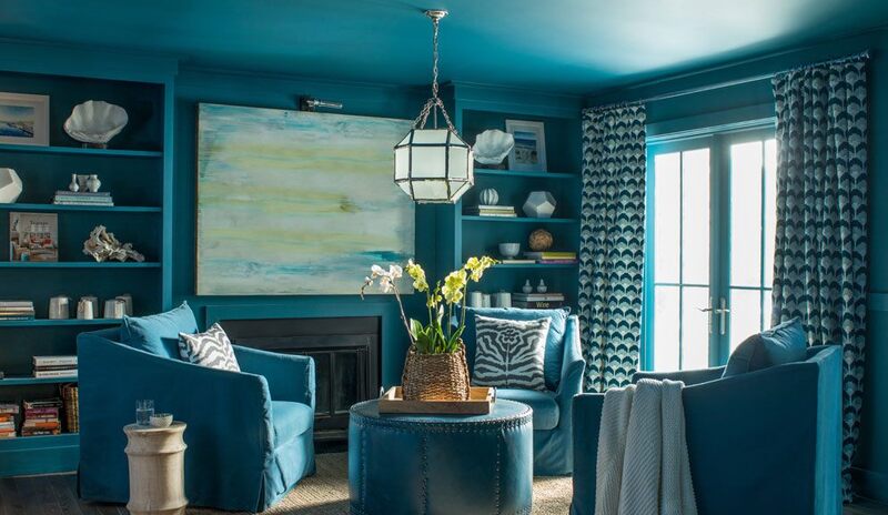 An all-blue painted living room with blue club chairs and built in shelving.