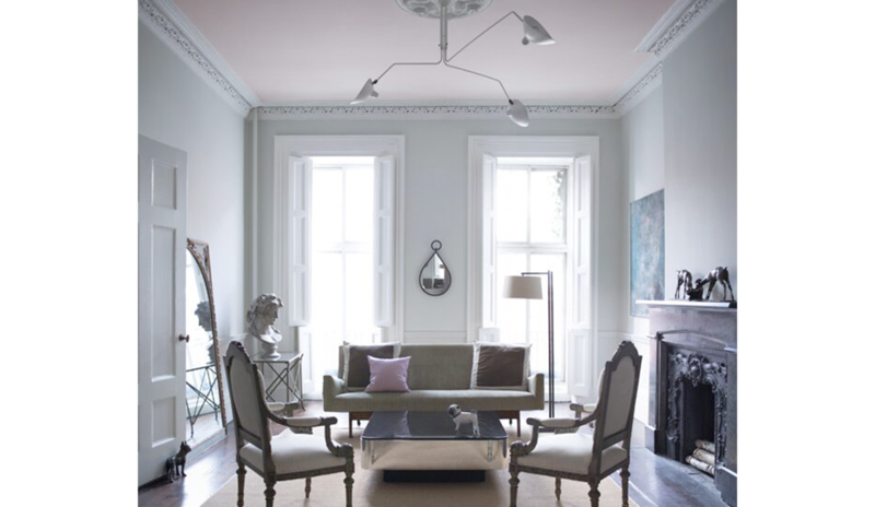A living room in a blue gray paint is accented by a pale pink ceiling.
