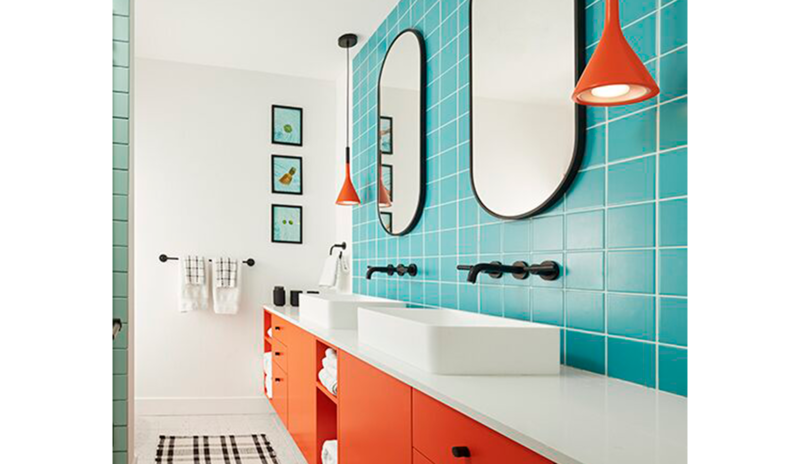 A bathroom with orange-red painted cabinetry, bright blue tile walls and white walls and ceiling. 