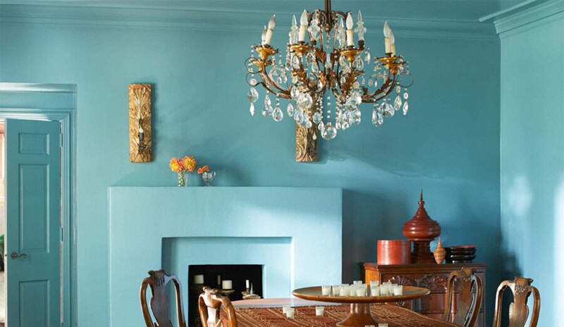 An opulent dining room with blue-painted walls, ceiling and fireplace