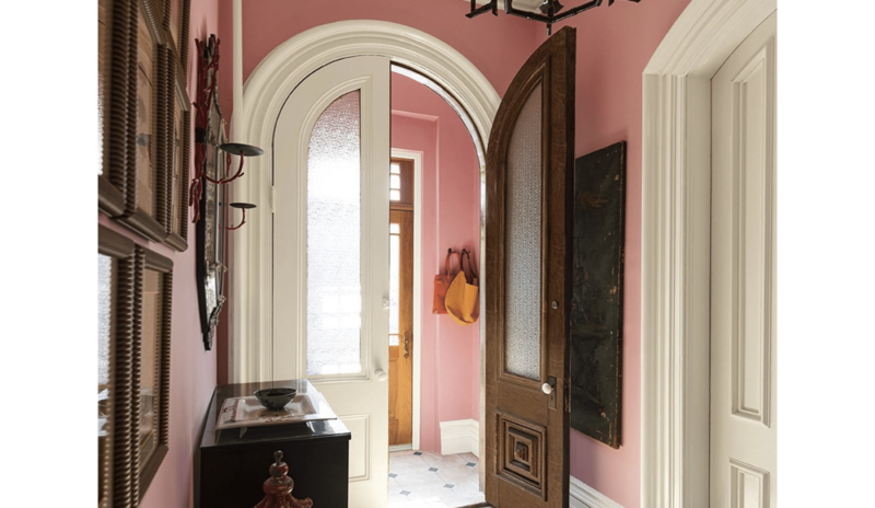 An entryway painted in Delicate Rose, with Niveous trim, a collection of wall art.