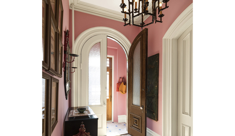 A traditional hallway and vestibule with pink-painted walls, white trim, doors, and ceiling