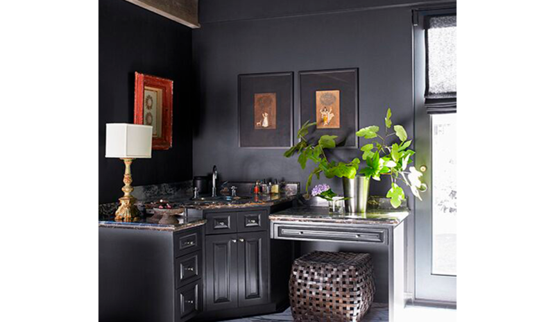 A dark gray entryway with mirror, door with large window, and an accent table with flowers on it.