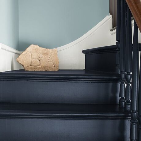 Sleek navy staircase with white trim against pale blue walls.