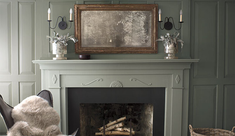A green-painted living room with matching green mantel and fur throw.
