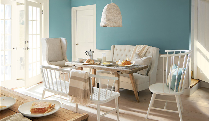 A well-lit dining room area with walls painted in Aegean Teal 2136-40.
