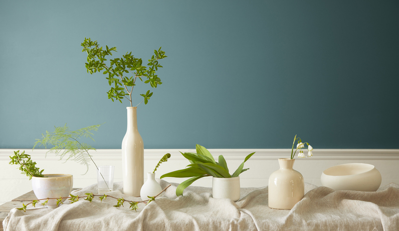 White vases and greenery on a table in front of a wall in Aegean Teal 2136-40.