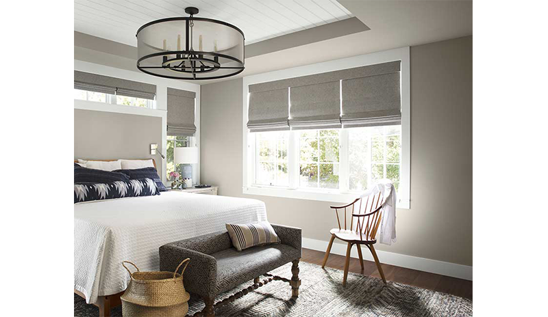 Un dormitorio neutral bien iluminado con una gran cama blanca y almohadas azules.