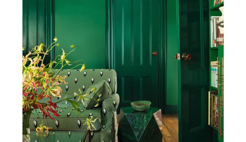 Sala verde con sofá estampado, mesa auxiliar de piedra, mesa de café de cristal y estanterías a jueg Sala verde con sofá estampado, mesa auxiliar de piedra, mesa de café de cristal y estanterías a jueg