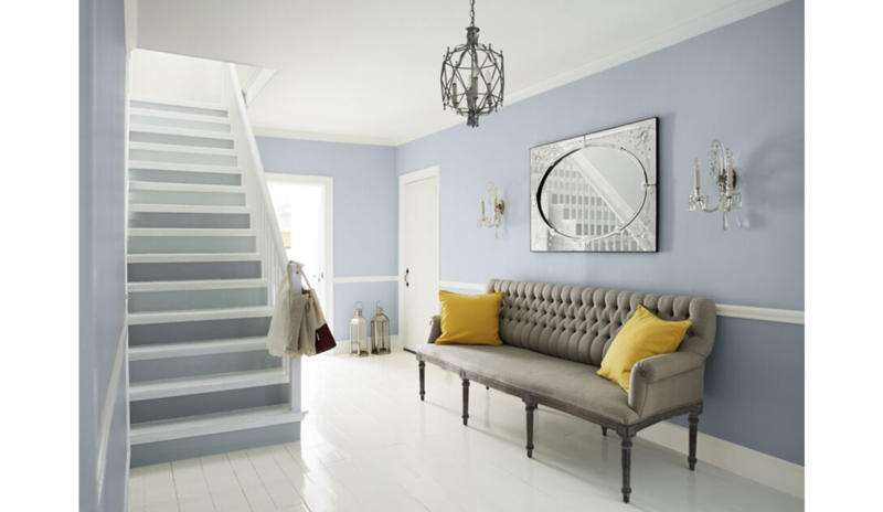 Área de estar azul-gris con escaleras de dos tonos, sofá gris y cojines amarillos, lámpara de araña Área de estar azul-gris con escaleras de dos tonos, sofá gris y cojines amarillos, lámpara de araña