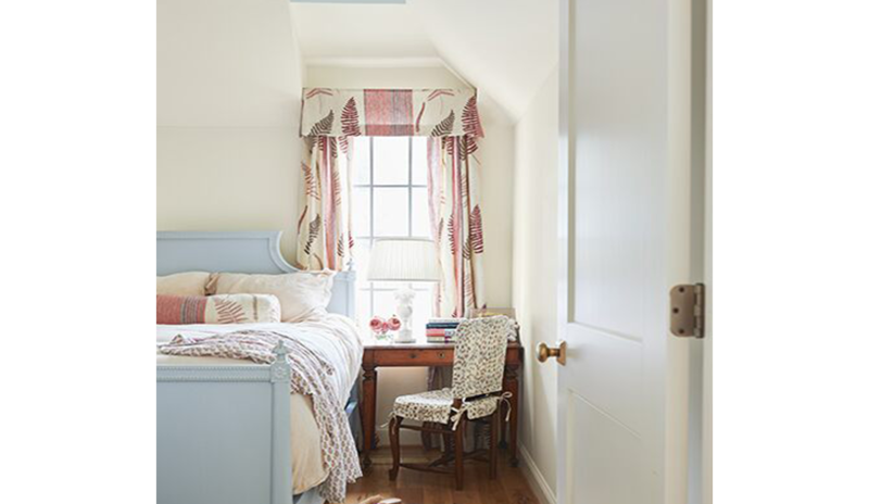 Cream bedroom, sky blue ceiling, a matching blue bedframe including light pink curtains and pillows