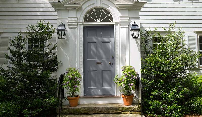 Una entrada frontal de estilo colonial con una puerta principal pintada de gris