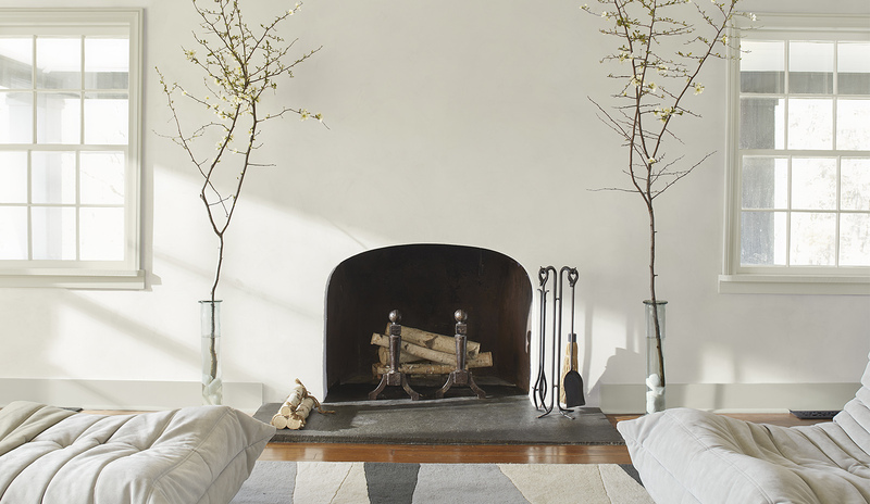 Una sala de estar pintada en blanco roto con una chimenea en forma de arco