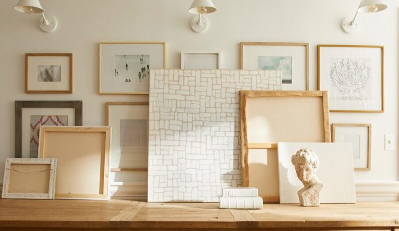 Pared galería blanca con matiz rosado, mesa de consola madera, marcos arte y apliques blanco crema.