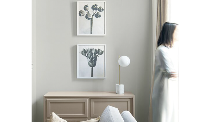 Light gray living room with two picture frames hanging above a wood cabinet next to a gray sofa.