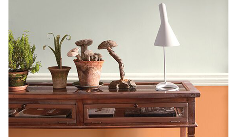 A split wall painted in cool gray and soft orange frames a wooden side table 