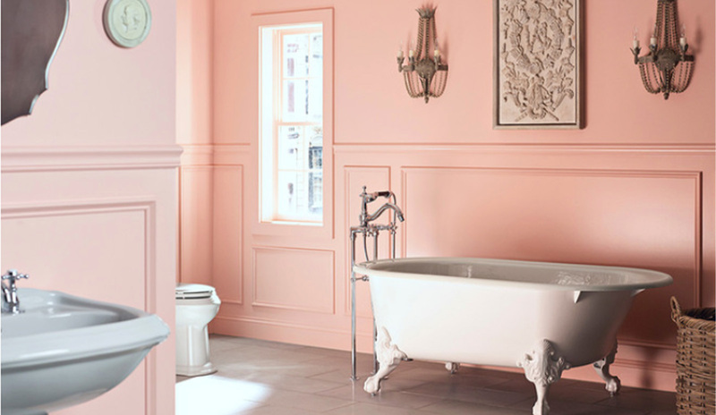 Bold pink-painted bathroom walls with matching wainscoting and a white clawfoot tub.