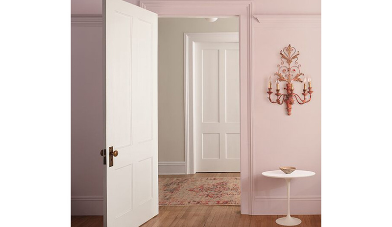 Light pink-painted walls with an open door leading out to a room with off-white-painted walls.