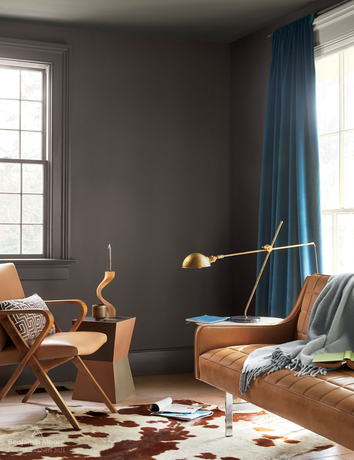 A contemporary modern living room with a cowhide rug, brown leather couches, and walls in Silhouette