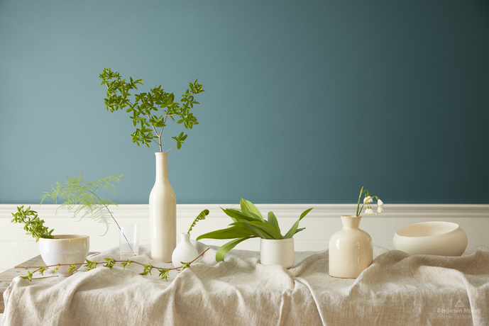 White vases and greenery on a table in front of a wall in Aegean Teal 2136-40.
