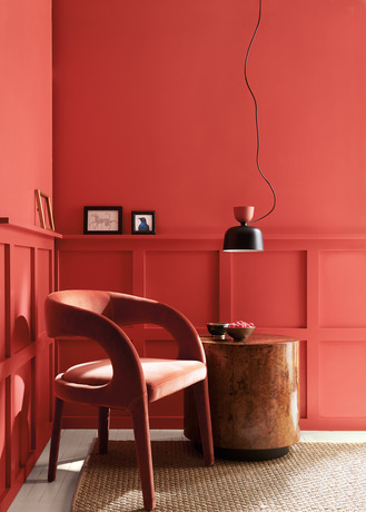 Raspberry Blush red-painted sitting room with mid century-style chair, wooden table and black lamp