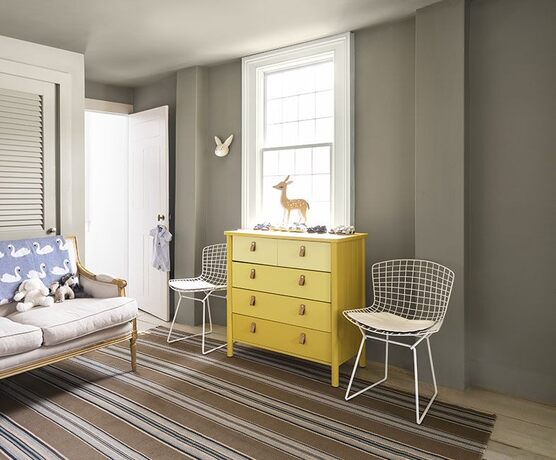 Sitting area: gray walls, greige sofa, metal basket chairs, ombré yellow dresser, deer statue & bunn