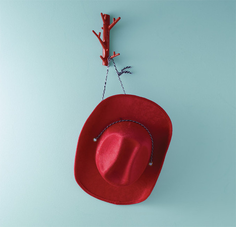 Una pared de color azul claro enmarca un sombrero de vaquero rojo.