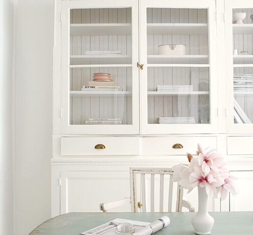 Un comedor de estilo shabby chic con paredes, muebles blancos, mesa en tono azul claro