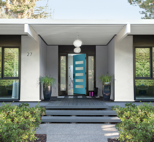 Una casa moderna de un solo piso en color gris con una puerta en color verde azulado.