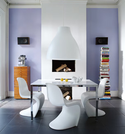 Una casa moderna con paredes lavanda, con una chimenea, mesa y sillas de comedor blancas