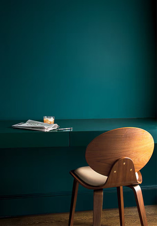 Un estudio pintado de azul con un escritorio pintado de azul y silla de madera moderna.
