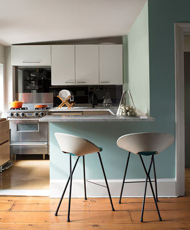 A compact kitchen, white cabinets, a marble countertop and stainless steel stove.
