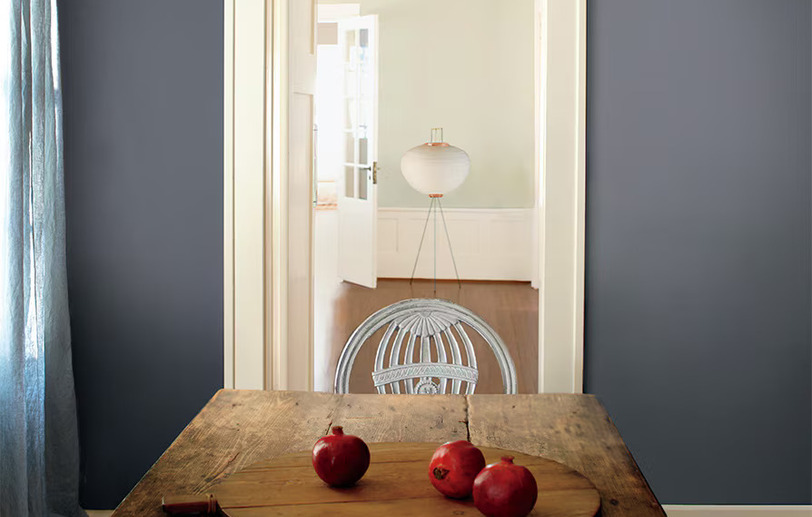 Mesa rústica de tablones con pared azul grisácea y granadas Mesa rústica de tablones con pared azul grisácea y granadas