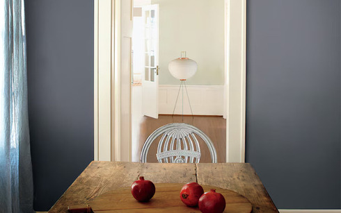 Mesa rústica de tablones con pared azul grisácea y granadas