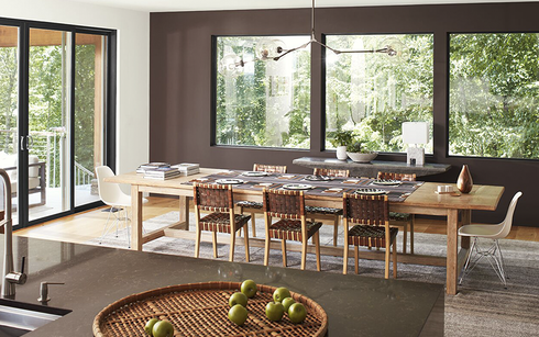 Comedor moderno con pared de acento marrón, techo blanco y puertas de vidrio, y una isla de granito 