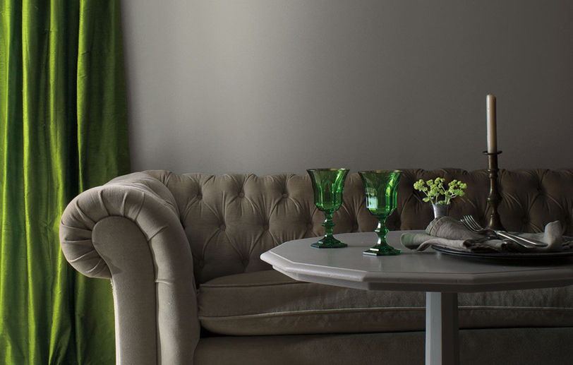 A living room with gray-painted walls, traditional gray couch, gray table with green accents.